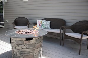 Relax in the outdoor seating area with a fire pit, wicker chairs, and a comfortable couch.