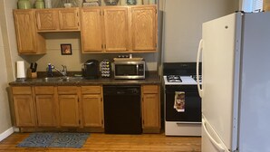 A kitchen with wooden cabinets, a dishwasher, a microwave, a stove, and a refrigerator. - Pet Friendly First Floor 2 Bedroom Apartment (St. Louis)
