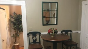 A dining area with a round table, two chairs, a potted plant, and a mirror on the wall. - Pet Friendly First Floor 2 Bedroom Apartment (St. Louis)