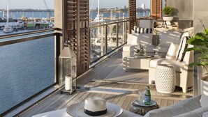 A balcony with a view of a marina, wicker furniture, and a potted plant.