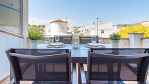 A patio with two wicker chairs and a table set for two, overlooking a residential area with white buildings and a clear sky. - Sant Maurici by Interhome (Empuriabrava)