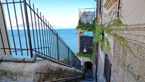 Un escalier étroit en pierre mène à un bâtiment d’où l’on a vue sur la mer.