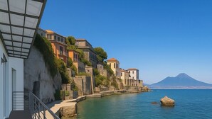 Une promenade en bord de mer offrant une vue dégagée sur la mer, une formation rocheuse et des bâtiments situés sur une colline.
