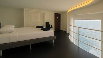 A modern bedroom with a bed, two chairs, a wardrobe, and a door.