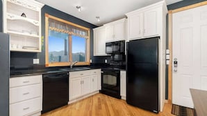 Una cocina moderna con armarios blancos, electrodomésticos negros y piso de madera.
