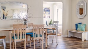 A dining area with wooden chairs and a table, a large mirror, and a view of a room with a window. - Sea La Vie - At the entrance to MacKerricher State Park and is in walking distance (Fort Bragg)