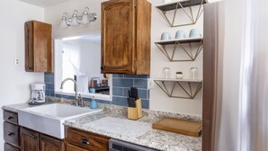 A kitchen with wooden cabinets, a granite countertop, a dishwasher, and a coffee maker. - Sea La Vie - At the entrance to MacKerricher State Park and is in walking distance (Fort Bragg)