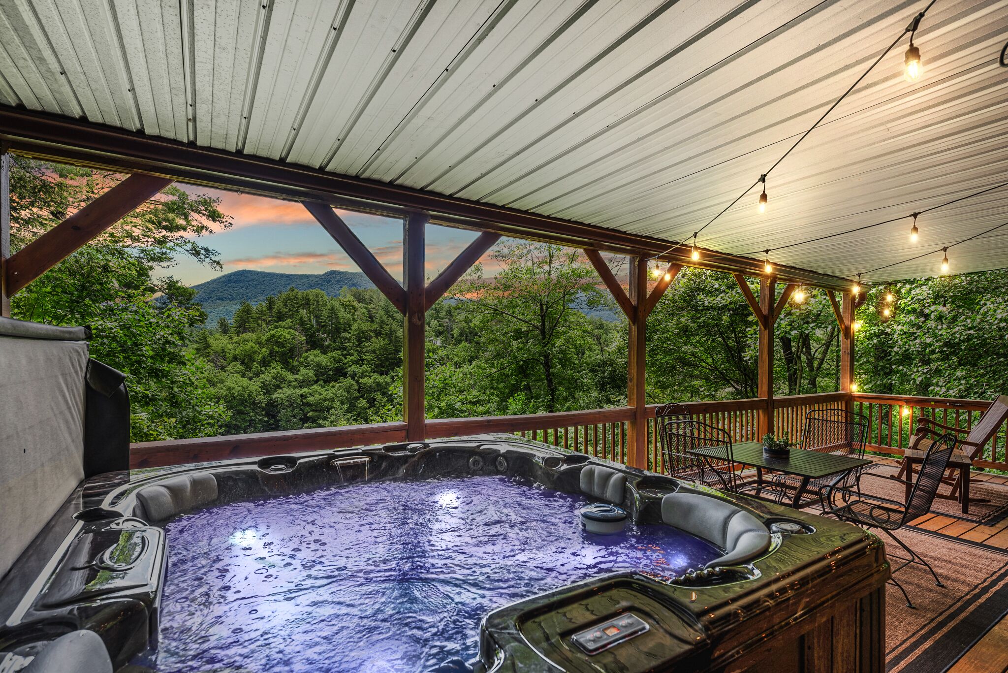 A hot tub with a wooden deck and a view of the mountains.