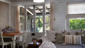 Una habitación acogedora con un ventanal grande, una mesa de madera con sillas y un sofá cómodo con cojines.