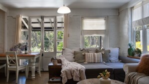 Una habitación acogedora con una mesa de madera, un sofá y una ventana con cortinas.