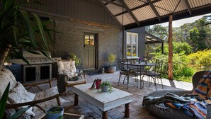 Un patio al aire libre con una parrilla, asientos y plantas en macetas.