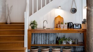 Un área de cocina con encimera de madera, un fregadero, un reloj y diversos utensilios de cocina.