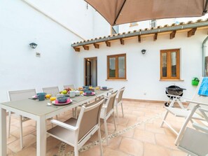 A dining area with a table set for four, surrounded by chairs. There are windows on the wall and a pergola overhead. - Can Monjo by Interhome (Andratx)
