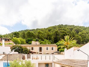 A building with a tiled roof, a balcony, and a view of a forested hill. - Can Monjo by Interhome (Andratx)