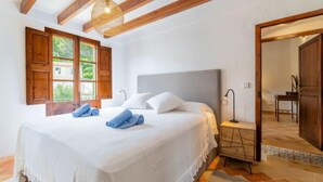 Ein Schlafzimmer mit einem großen Bett, Holzbalken, einem Fenster mit Blick und einem Nachttisch mit Lampe.