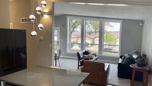 Eine moderne Küche mit einer großen Kochinsel, ein Essbereich mit Tisch und Stühlen sowie ein Wohnzimmer mit Sofa und Couchtisch.
