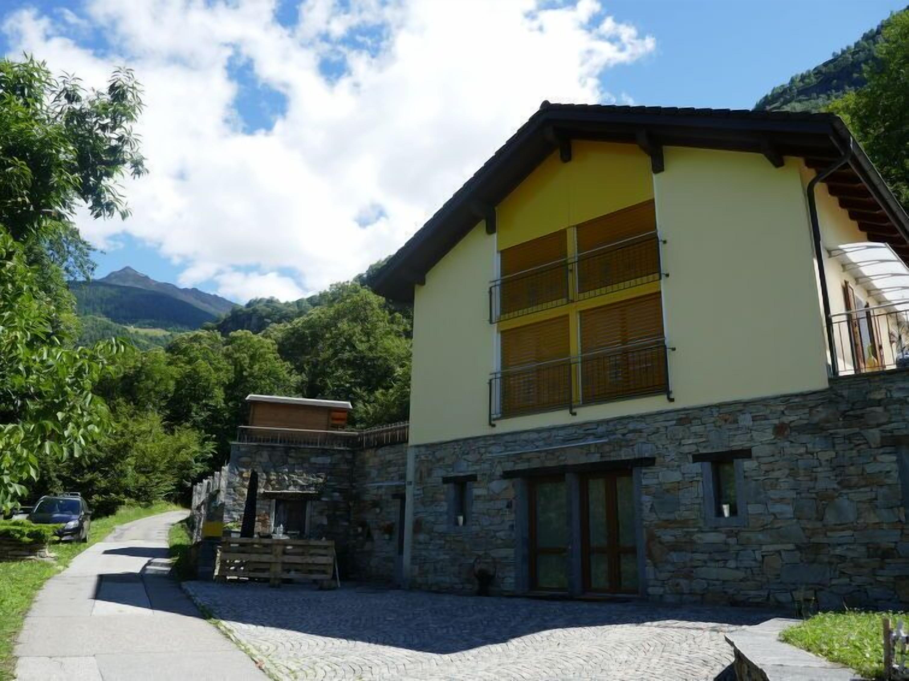 Un immeuble de deux étages avec une façade en pierre, de grandes fenêtres et un balcon.