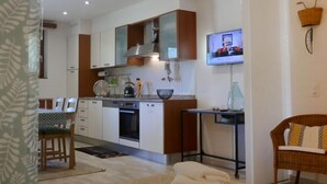 A modern kitchen with white cabinets, a built-in oven, and a TV mounted above the counter. - Open Space with Patio "Lety" by Interhome (Malvaglia)
