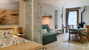 A modern bedroom with a bed, a green sofa, a dining table with chairs, and a large window. - Open Space with Patio "Lety" by Interhome (Malvaglia)