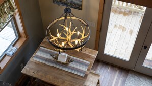 Un tavolo da pranzo in legno con una lampadario, una finestra e una porta che dà sull'esterno.