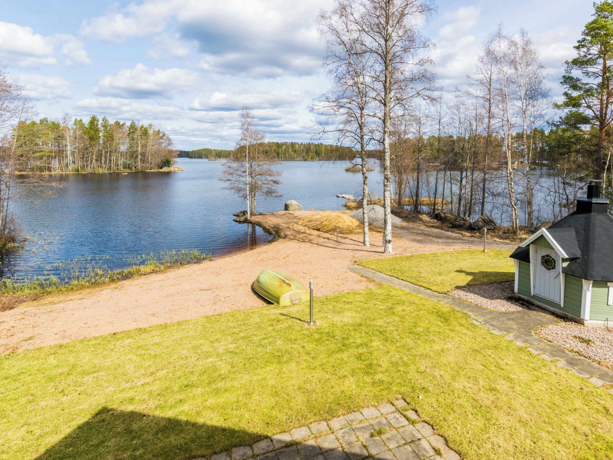A lakeside property with a grassy area, a small shed, and a boat.