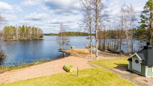 A lakeside property with a dock, a small boat, and a cabin.