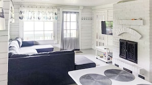 A modern living room with a sofa, a dining table with placemats, a fireplace, and a television.