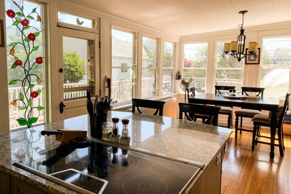 A kitchen with a granite countertop, stainless steel appliances, and a dining area with a table and chairs.