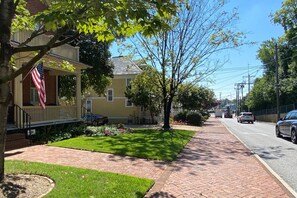 A residential street with a house featuring a front porch and an American flag.