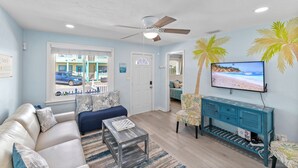 A living room with a sofa, coffee table, and a TV mounted on the wall. - 2-Min Walk to Beach, 3 Cars, 3BR Family Escape walkable to Boardwalk (Daytona Beach)