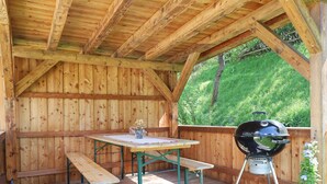 Eine Terrasse aus Holz mit Picknicktisch, Grill und Bank.
