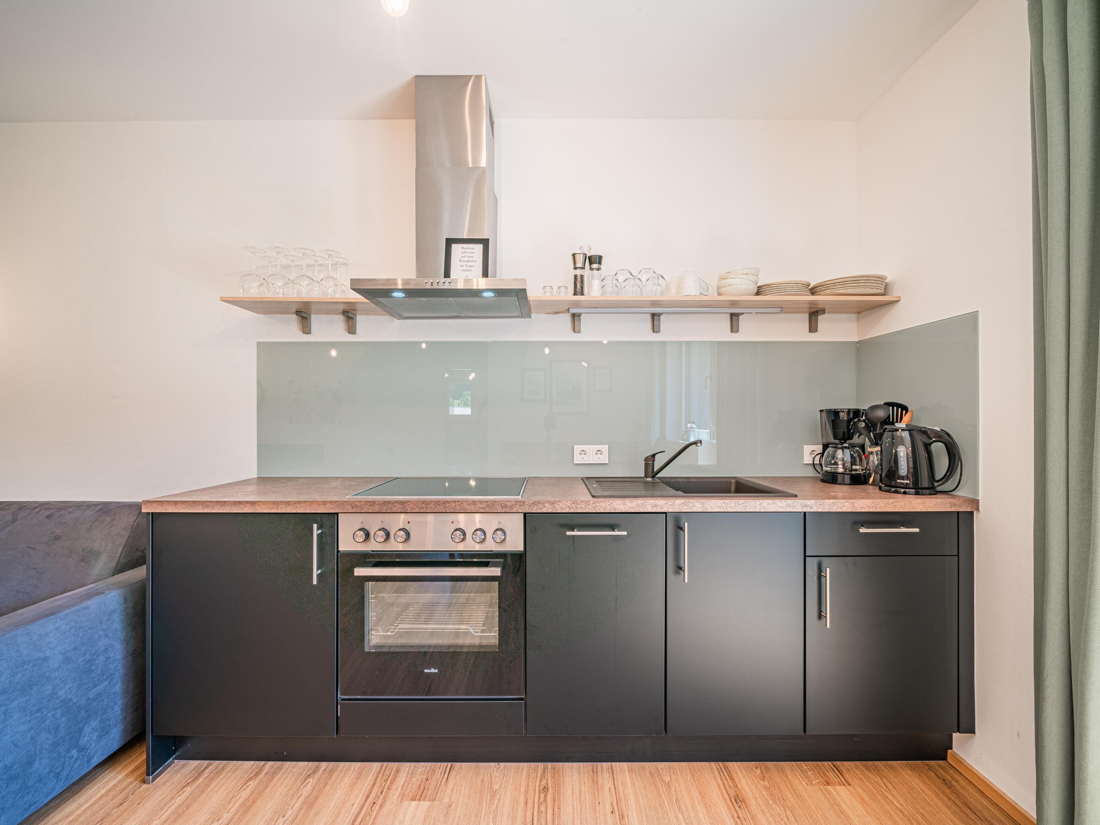 Una cocina moderna con horno empotrado, campana extractora de acero inoxidable y espacio para café.