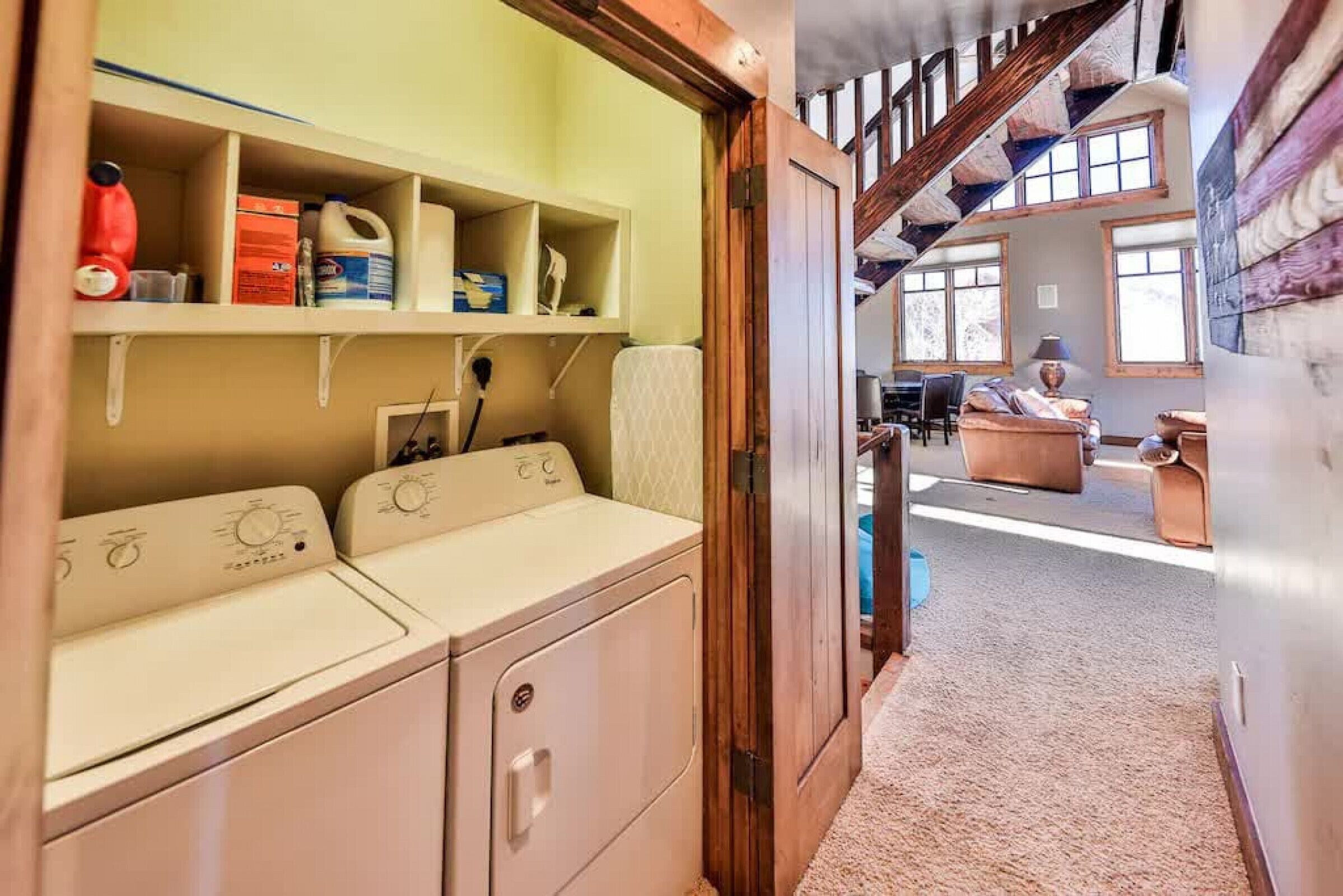 A laundry area with a washing machine and shelves with cleaning supplies.