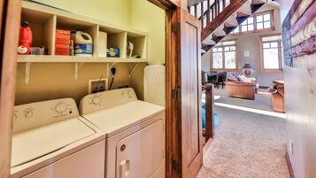 A laundry area with a washing machine and shelves with cleaning supplies.