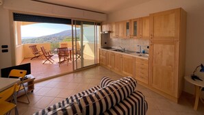 A modern kitchen with wooden cabinets, a dining area with a table and chairs, and a sofa.