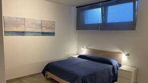 Een slaapkamer met een bed, nachtkastjes, een raam en decoratieve wandkunst.