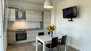Een moderne keuken met witte kasten, een gasfornuis en een eethoek met een tafel en stoelen.
