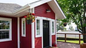 Een rood huis met een zwarte deur, witte ramen en een veranda met treden.