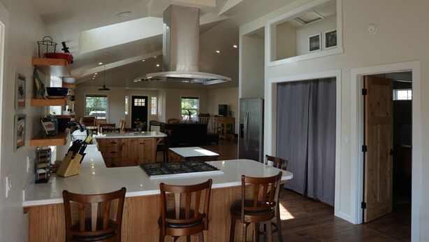 Een ruime keuken met een groot eiland, houten stoelen en inbouwplanken.