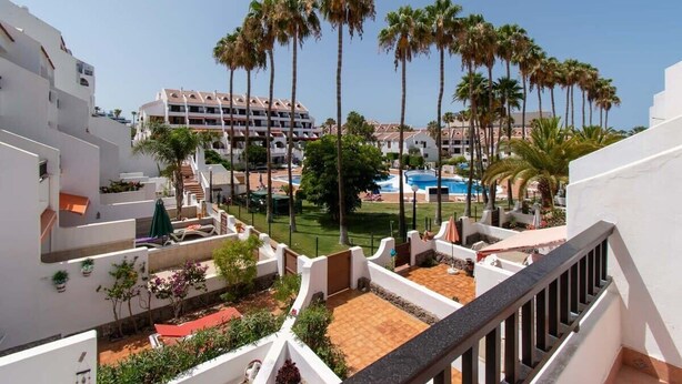 A hotel courtyard with palm trees, a pool, and a white building with balconies. - Parque Santiago II 131 - One Bed Duplex with Pool (Playa de las Americas)