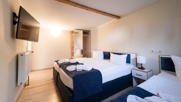 Une chambre d’hôtel avec deux lits, une télévision, une table de chevet avec une lampe et un dressing.