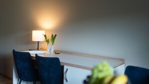 Un coin repas comprenant une table, des chaises, une lampe et un vase avec des plantes.