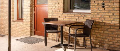 Un bâtiment en briques avec une porte en bois, une fenêtre et une table avec deux chaises.