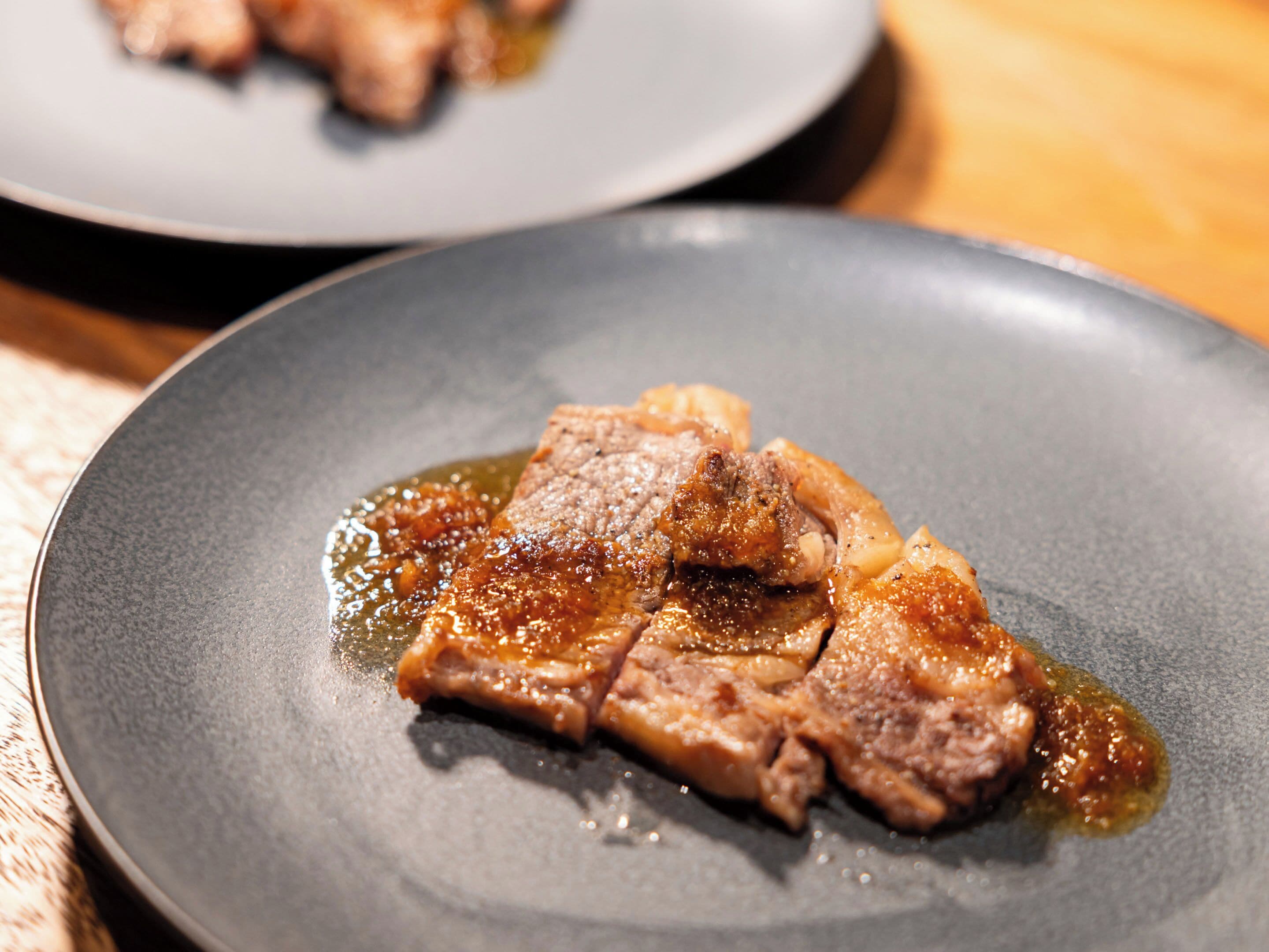 A close-up of a dish with meat and sauce on a plate.
