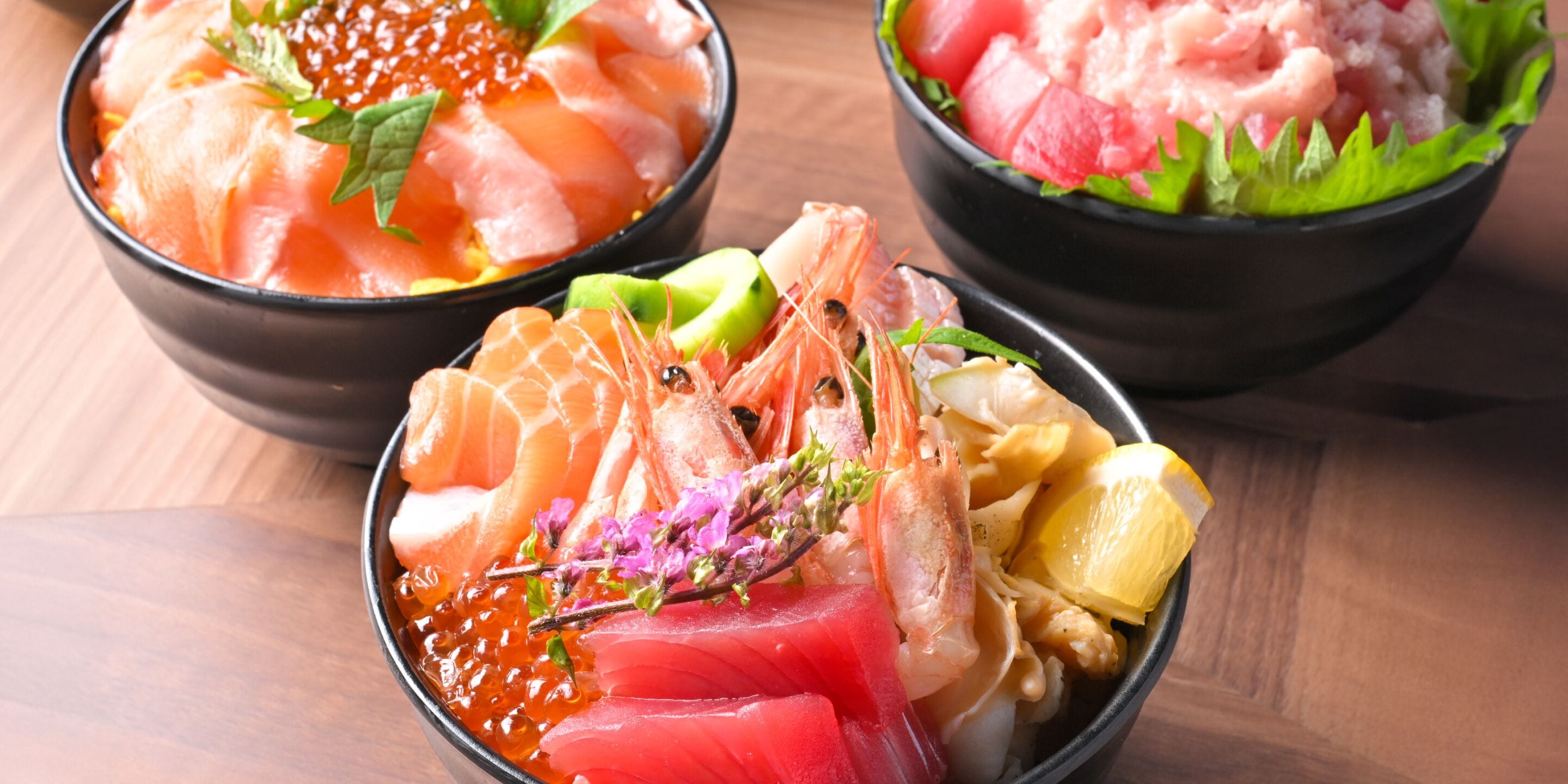 Three bowls of sashimi with various toppings.