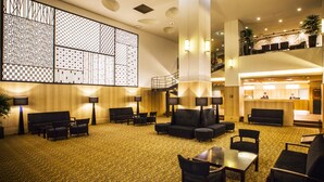 A spacious lobby with multiple seating areas, a reception desk, and a staircase leading to an upper level.