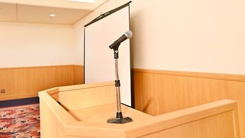 A conference room with a podium, a microphone, and a projection screen.