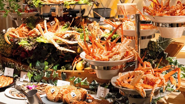 A buffet with various seafood dishes, including crab legs and fish, arranged on multiple serving platters.