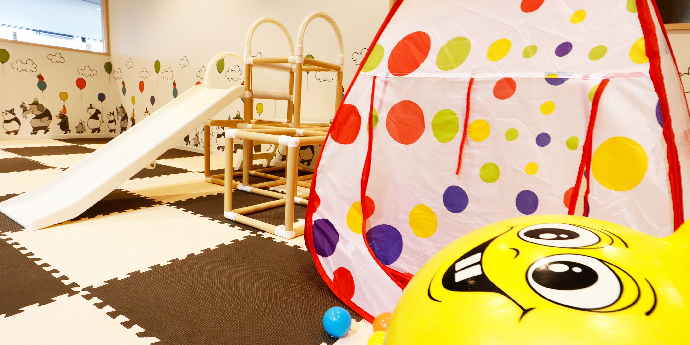 A play area with a slide, a climbing structure, and a tent-like playhouse.