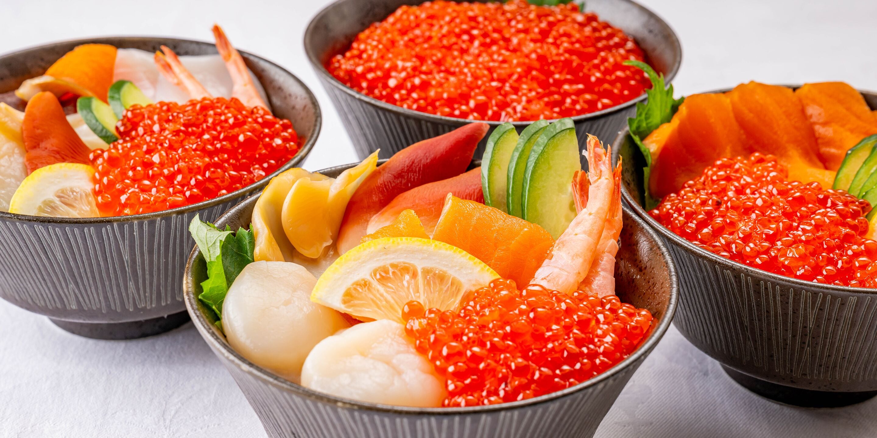 Tres cazos de sashimi con diversos mariscos y guarniciones.